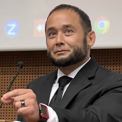 Jeremy Seda formally dressed, standing at a podium presenting at the American University of Beirut's ABLE Summit
